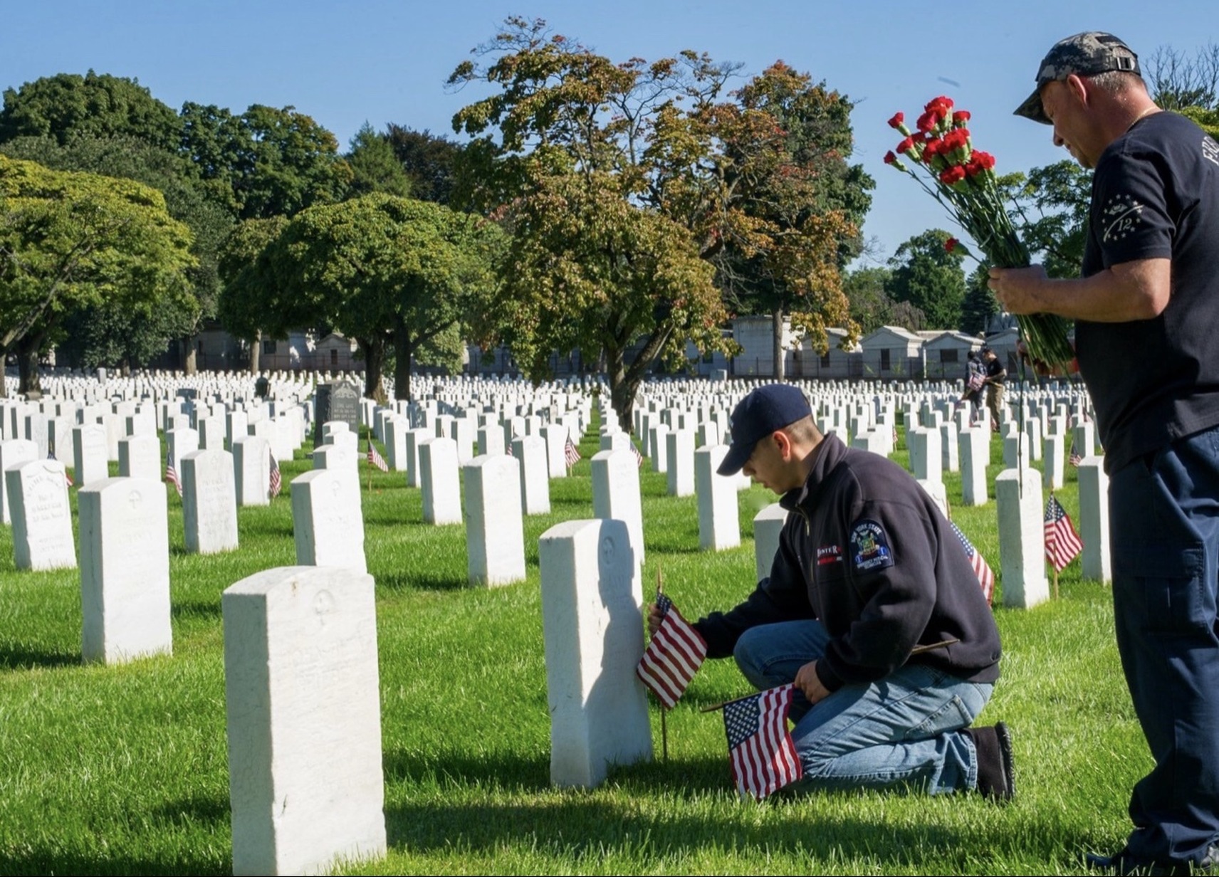 Volunteers placing flags at headstones in a national cemetery