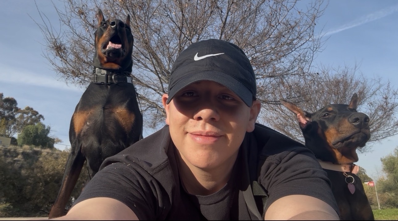 Anthony taking a selfie outdoors with Ace and Kira, his two Dobermans