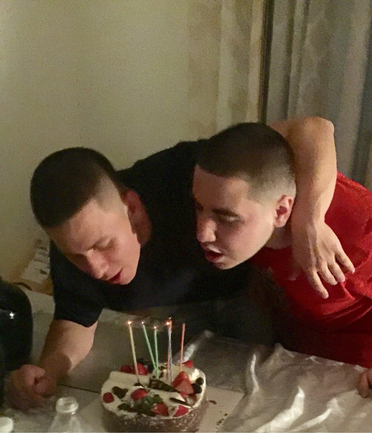 Anthony and his brother Mario leaning in together to blow out birthday candles